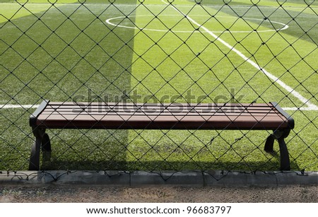 brown wood bench with metal legs beside indoor synthetic grass soccer field,Korat,Thailand.
