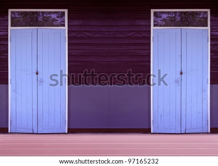 Vintage old school blue wooden door at brown wood panel and wooden floor.