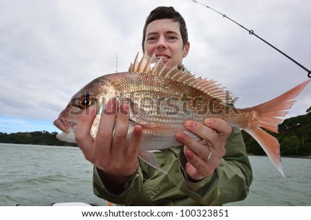 A man holds a fish that he caught during fishing at sea on a fishing boat.