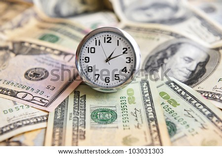 A clock show the time over American one hounded Dollar bank notes. Business concept time is money\
,