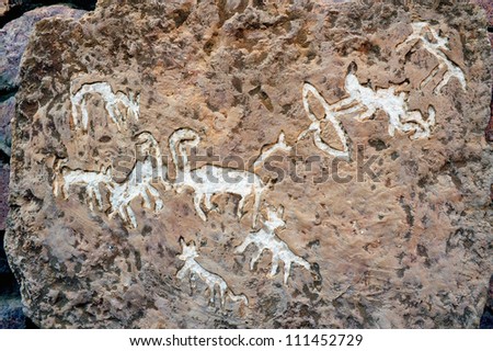 Rock drawings of hunting story on a carved stone in Timna Park, Israel.