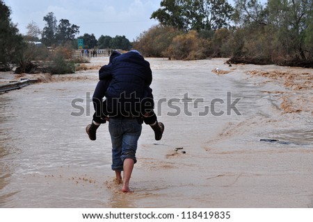 SOUTH ISRAEL - JANUARY 18: Travelers are trying to cross a flash flood in Nahal Habsor Israel, on January 18 2010 .Flash floods in Israel are deadly people are killed by them each year