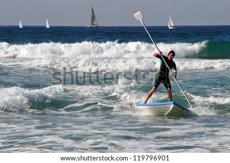 ASHDOD - JAN 16: A man rides a Hasake on January 16 2010 in Ashdod,Israel. It\'s Israeli SUP Surfing board dating back to the 8th century A.D.
