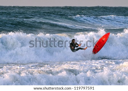 ASHKELON - DEC 12: Wave surfer surfing wave at sea on December 12 2009 in Ashkelon, Israel.It originated by Polynesian people and was first discovered by Captain Cook in 1778.