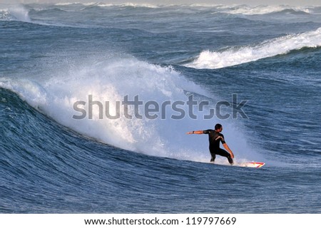 ASHKELON - DEC 12: Wave surfer surfing wave at sea on December 12 2009 in Ashkelon, Israel.It originated by Polynesian people and was first discovered by Captain Cook in 1778.