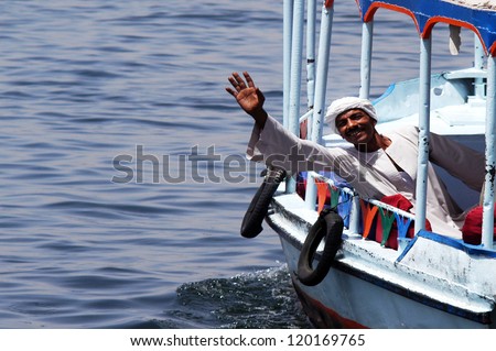 LUXOR - MAY 02:Egyptian man wearing traditional Jalabiya wave hello on a boat on May 02 2007 in Luxor  Egypt. It\'s oversize long sleeved shirt that covers the entire body