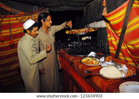 WADI RUM-NOV 10:Arab men cook Maqluba in Wadi Rum,Jordan on November 10 2007.It\'s a traditional dish of the Arab Levant of meat, rice and fried vegetables in a pot that flipped upside down when served