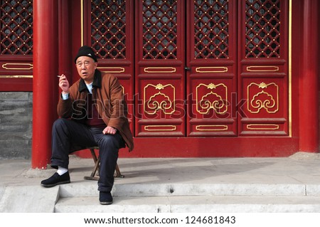BEIJING - MARCH 14:Chinese man smoke cigarette outside old house in Hutong on March 14 2009 in Beijing, China. Chinese consume 3 million cigarettes every minute