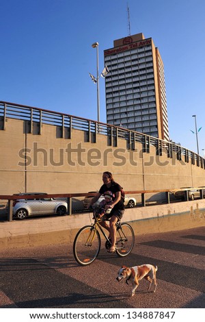TEL AVIV, ISRAEL - NOV 17:Man rides bicycles and man walking dog along Tel-Aviv beach in Tel Aviv, Israel.The \