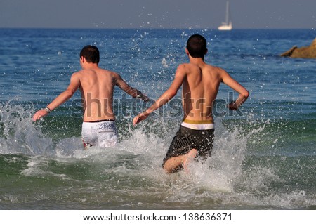 ASHDOD - JAN 09:Young Israeli men runs to the sea on a very hot day on Jan 09 2010.The highest recorded temperatures in Israel was 129 Fahrenheit  Degrees (54 Celsius) in Tirat Tsvi on June 21 1942.