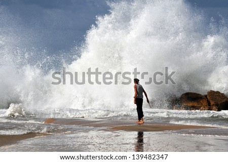 ASHKELON - NOV 02:Israeli man walk into a giant wave on Nov 02 2009.According to a recent research about consequences of rising sea levels, a six-meter tsunami waves can strikes Israel\'s coast.