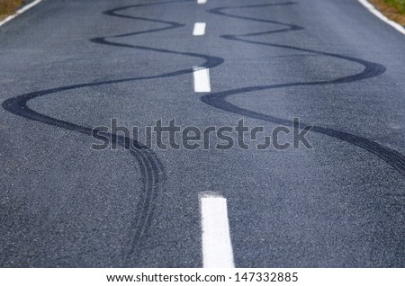 Winding skid marks of a vehicle on a street road.
