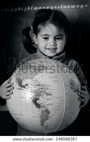 AUCKLAND, NZ - JULY 26:A girl (Talya Ben Ari age 3) holds a globe during geography lesson on July 26 2013. The oldest known world maps date back to ancient Babylon from the 9th century BC.