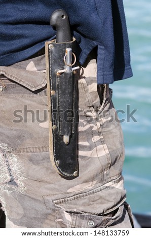 An hunting survival knife carry by a man on his belt outdoor.