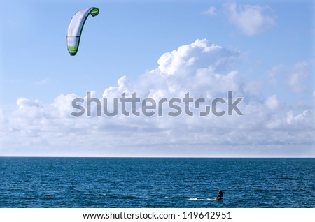 Man Kite surfing or Kite boarding, adventure surface water sport, combination of the wake boarding, windsurfing, surfing, paragliding, and gymnastics into one extreme sport