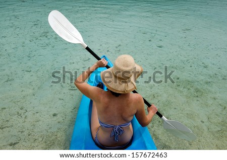 Young caucasian woman kayaking in sea at over turquoise water during travel vacation in a tropical Island.Rarotonga Cook Islands. Concept photo of women freedom, travel, vacation.