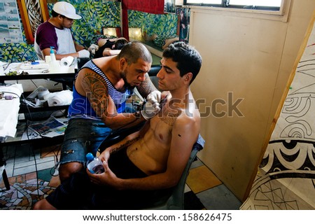 RAROTONGA - SEP 21:Tattoo artist draws a design on a chest of a young man on Sep 21 2013.The National Geographic states that in April 2000, 15% of Americans (40 million people) were tattooed.
