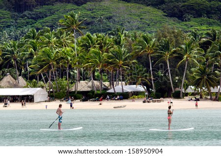 RAROTONGA - SEP 16:Man and a woman stand up paddle boarding over Muri Lagoon on Sep 16 2013.Cooks Islands are largely unspoiled by tourism with only 100,000 visitors a year.