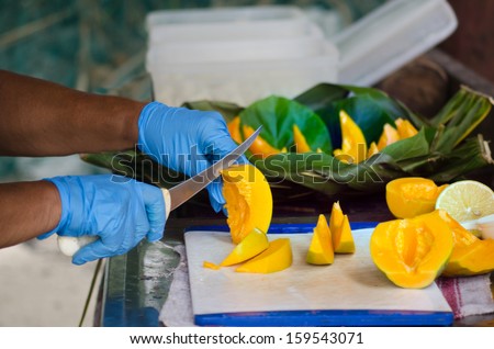 Chef hands slice Papaya fruit in outdoor kitchen on Pacific Island