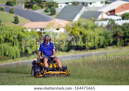 CABLE BAY - NOV 04:Man rides on lawn mower on Nov 04 2013.The first mechanical grass-cutting device appeared in 1830 by English textile worker named Edwin Budding from England.