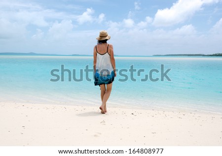 Young woman walks barefoot on deserted tropical island in Aitutaki Lagoon Cook Islands