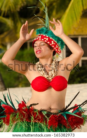 Portrait of Polynesian Pacific Island Tahitian female  dancer  in colorful costume dancing on tropical beach with palm trees in the background.