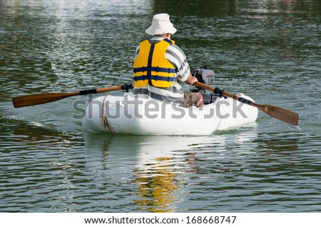Man rows a rubber inflatable dinghy boat.