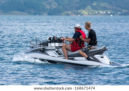 BAY OF ISLANDS,NZ - DEC 12:Two men rides personal water craft on Dec 12 2013.Operating a PWC can involve a risk of body orifice injuries and fuel discharge can contaminates the wildlife environment.