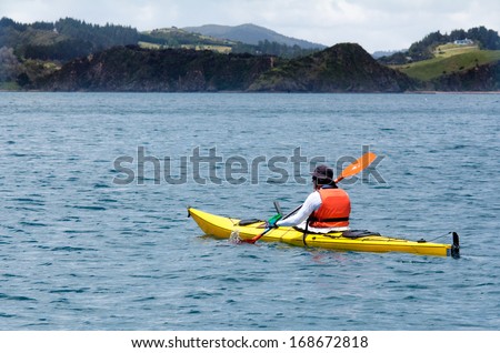 Man rows a yellow sea kayak in the bay of Island New Zealand. Very popular travel destination of NZ