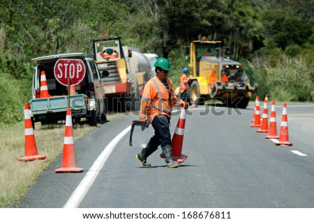 CABLE BAY, NZ - DEC 12:Road worker slows traffic with stop sign on Dec 12 2013.The Road Maintenance crew has the responsibility for the day-to-day maintenance needs of the road system.