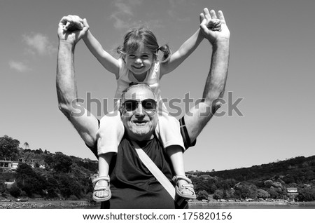 Granddad carry his grandchild on his shoulder during summer vacation. (BW)