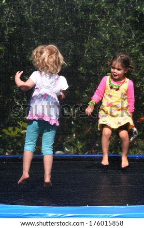 Two happy girls jumps on a trampoline.