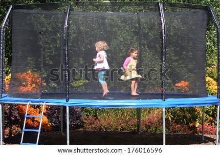 Two happy girls jumps on a trampoline.
