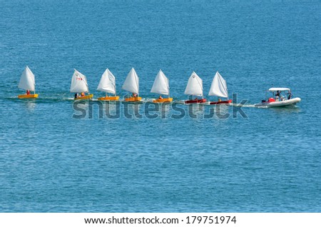 DOUBTLESS BAY, NZ - FEB 15:Motor boat with sailing instructor drags a line of small sailing boats on Feb 15 2014.New Zealand is one of the top sailing nation in the world.