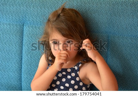 Little girl (age 3-4) sucks thumb at home. Concept photo of healthcare and early childhood