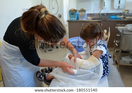 KAITAIA, NZ - MAR 06:Nurse apply orthopedic cast wrapped on a little girl (Talya Ben-Ari age 3) in hospital room on Mar 06 2014.Forearm fractures account for 40% to 50% of all childhood fractures.