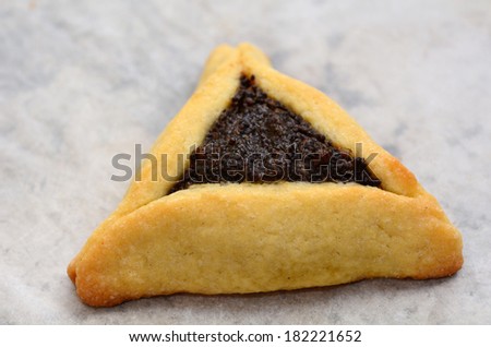 One big backed Hamentashen, Ozen Haman, Purim cookie for the Jewish holiday Purim. Isolated on baking paper. (Copy space)