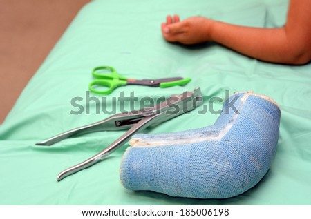 Removed child arm cast on hospital bed with child recovered arm in the background.Concept photo of child, children, health care,outdoor accidents, game accidents, playground accidents, home accidents.