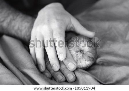 Hands of a man and woman in bed with apple. Concept photo for sex health care, sex life, seduction, sexual, sexuality, relationship, sex problems, desire, lust, love.