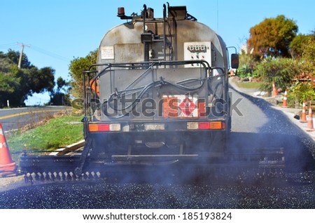 CABLE BAY, NZ - APR 01 2014:Tar truck vehicle tarring a piece of new road during roadwork construction. There are more than four million miles of highways and roads in the U.S alone.