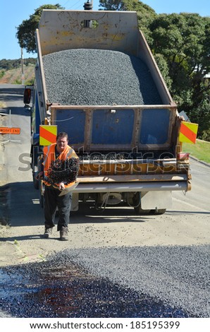 CABLE BAY, NZ - APR 01 2014:Road worker spreading new gravel during roadwork. There are more than four million miles of highways and roads in the U.S alone.