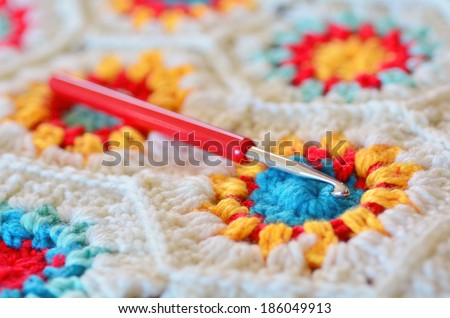 Crochet hook needle on granny square blanket. Concept photo of handmade art and crafts