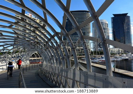 MELBOURNE,AUS - APR 14 2014:Cyclist and pedestrian cross on Webb Bridge.It\'s an award winning bridge forming a cycling and pedestrian link to the main part of Docklands, through Docklands Park.