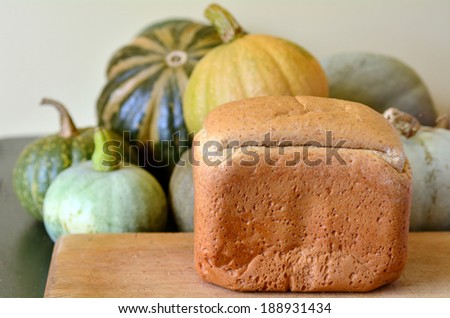Pumpkin bread on wooden board in a farm house kitchen with pumpkins selection in the background.