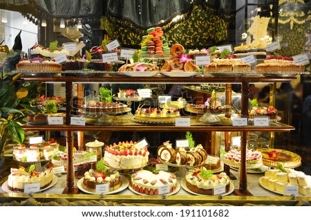 Pastry shop display window with variety of cakes.