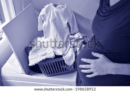 Pregnant housewife woman doing housework, washing family clothes, during pregnancy.Concept photo of pregnancy, pregnant woman lifestyle and health care. crop image - copyspace (BW)