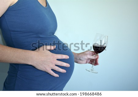 Pregnant woman want to drink alcohol (red wine) during pregnancy .Concept photo of pregnancy, pregnant woman lifestyle and health care. crop image - copyspace