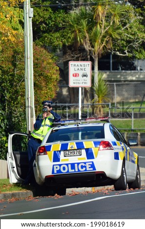 AUCKLAND,NZ - JUNE 03 2014:Traffic Police officer pointing his radar gun at speeding traffic.Traffic Police Monitor traffic to ensure motorists observe traffic regulations and safe driving procedures.