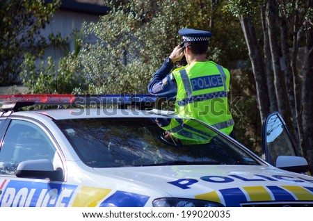 AUCKLAND,NZ - JUNE 03 2014:Traffic Police officer pointing his radar gun at speeding traffic.Traffic Police Monitor traffic to ensure motorists observe traffic regulations and safe driving procedures.