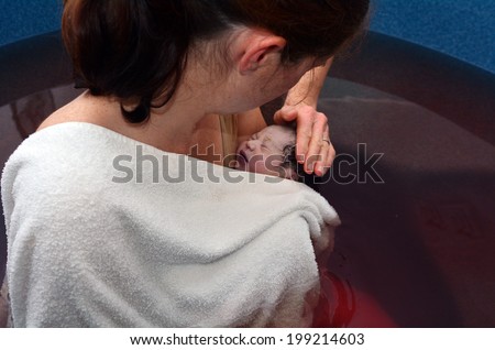 AUCKLAND - JUNE 07 2014:Woman holds her baby in a pool after natural water birth.Women have been using water in labour and birth for thousands of years.